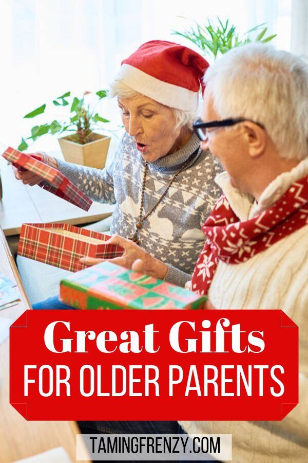 older couple opening gifts in front of Christmas tree