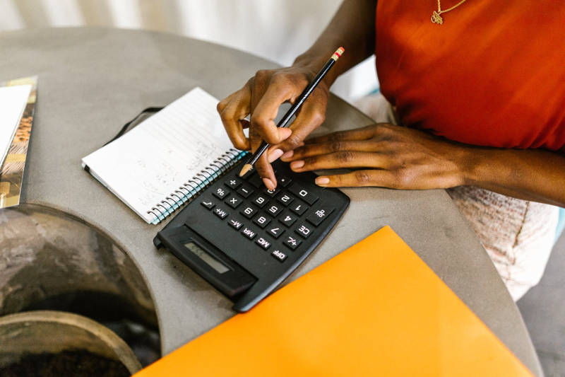 female  hands with calculator and spiral notebook